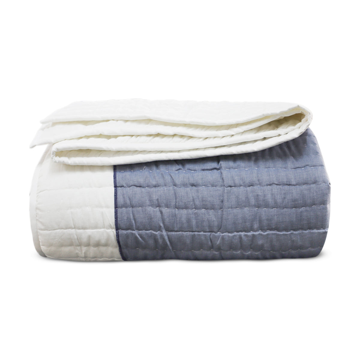 Neatly folded Blue Stonehenge Appliqué Quilt showing a dusty blue textured panel stitched alongside a solid white channel-quilted segment.