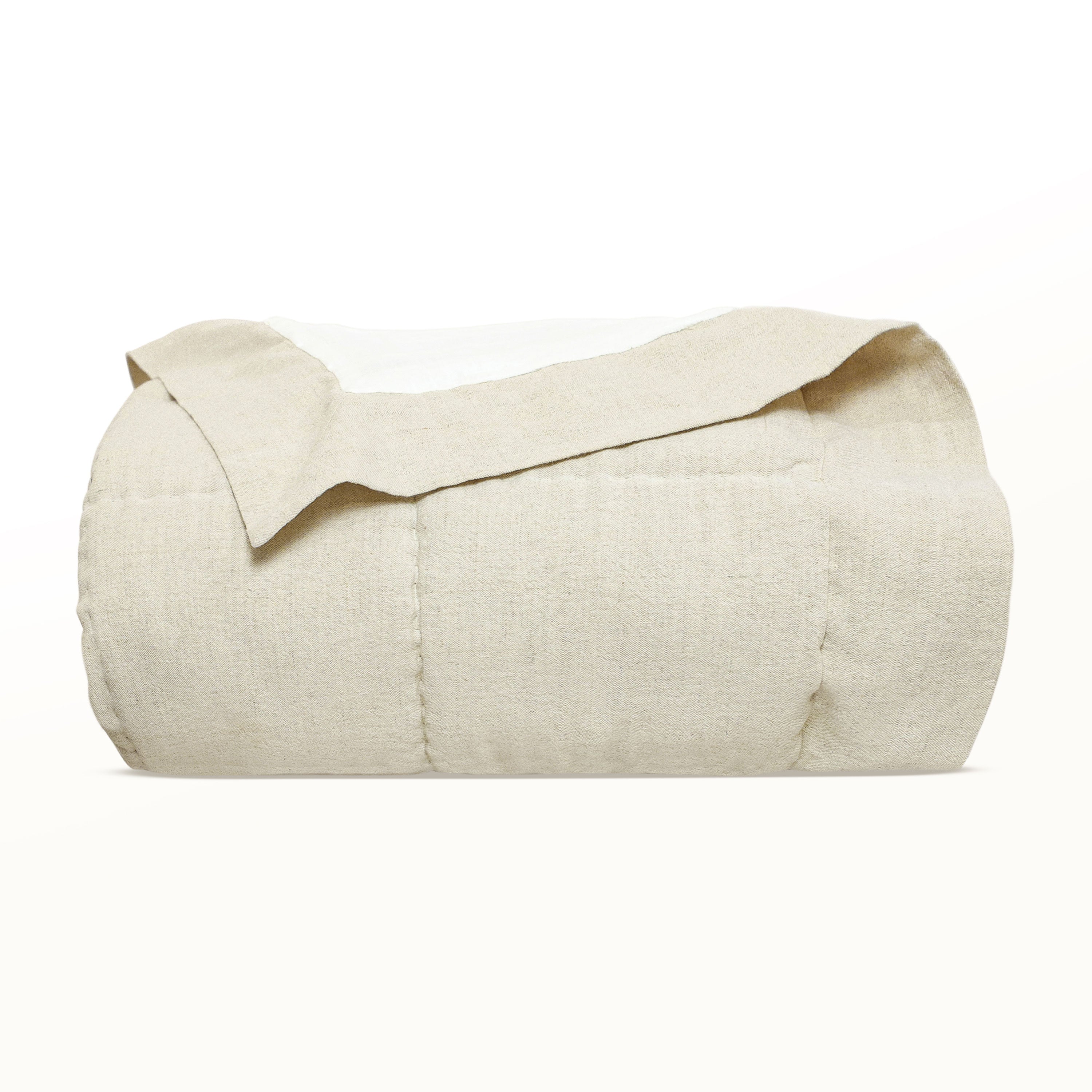 Folded beige textured linen quilt showcasing broad box quilting patterns and a matching wide linen border fabric.