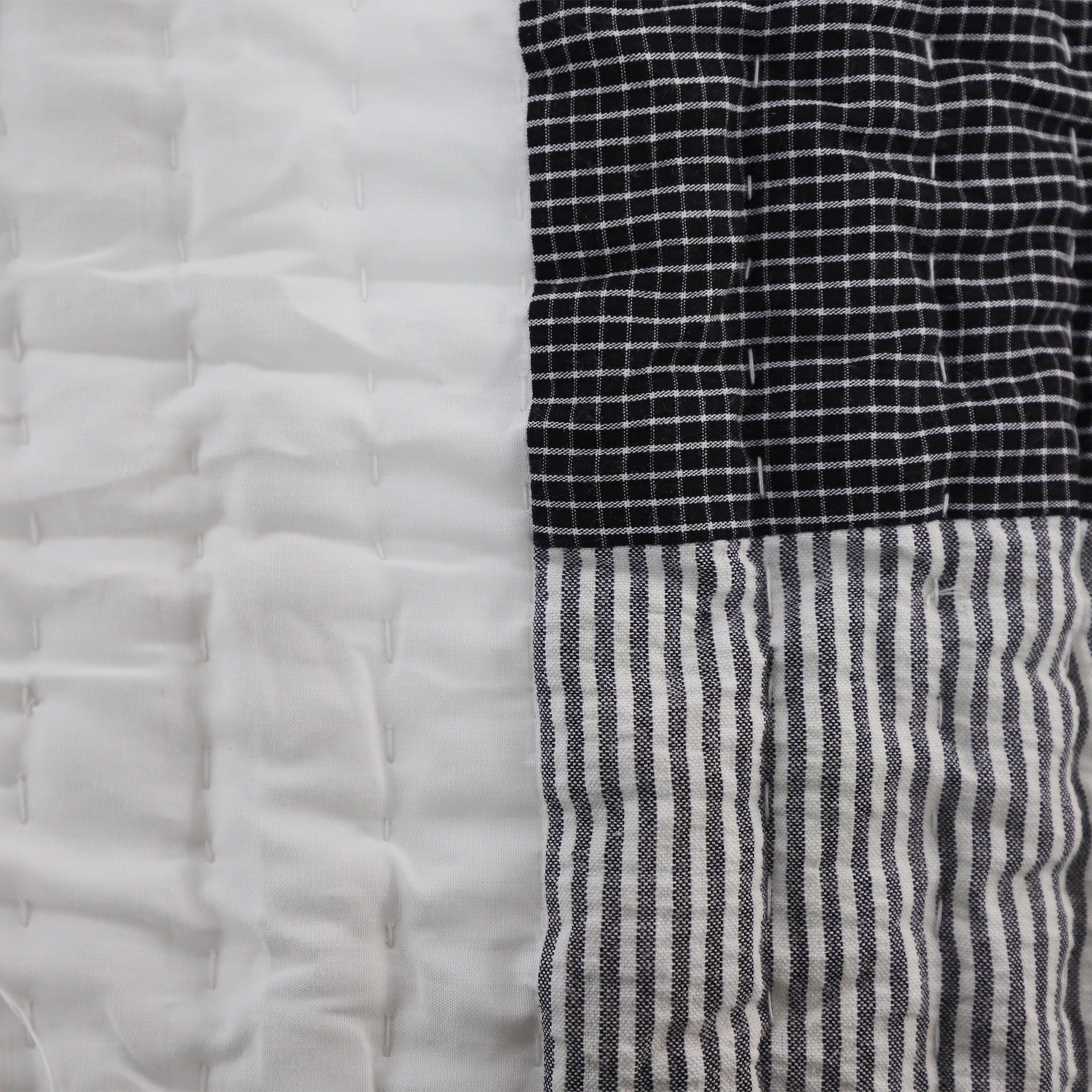 Close-up of cotton patchwork quilt revealing detailed stitching and bold contrast between ivory, black, and grey sections. Brings visual interest and soft comfort to dorm bedding. Reversible, breathable, and low-maintenance. Perfect for daily use in a fast-paced college setting.