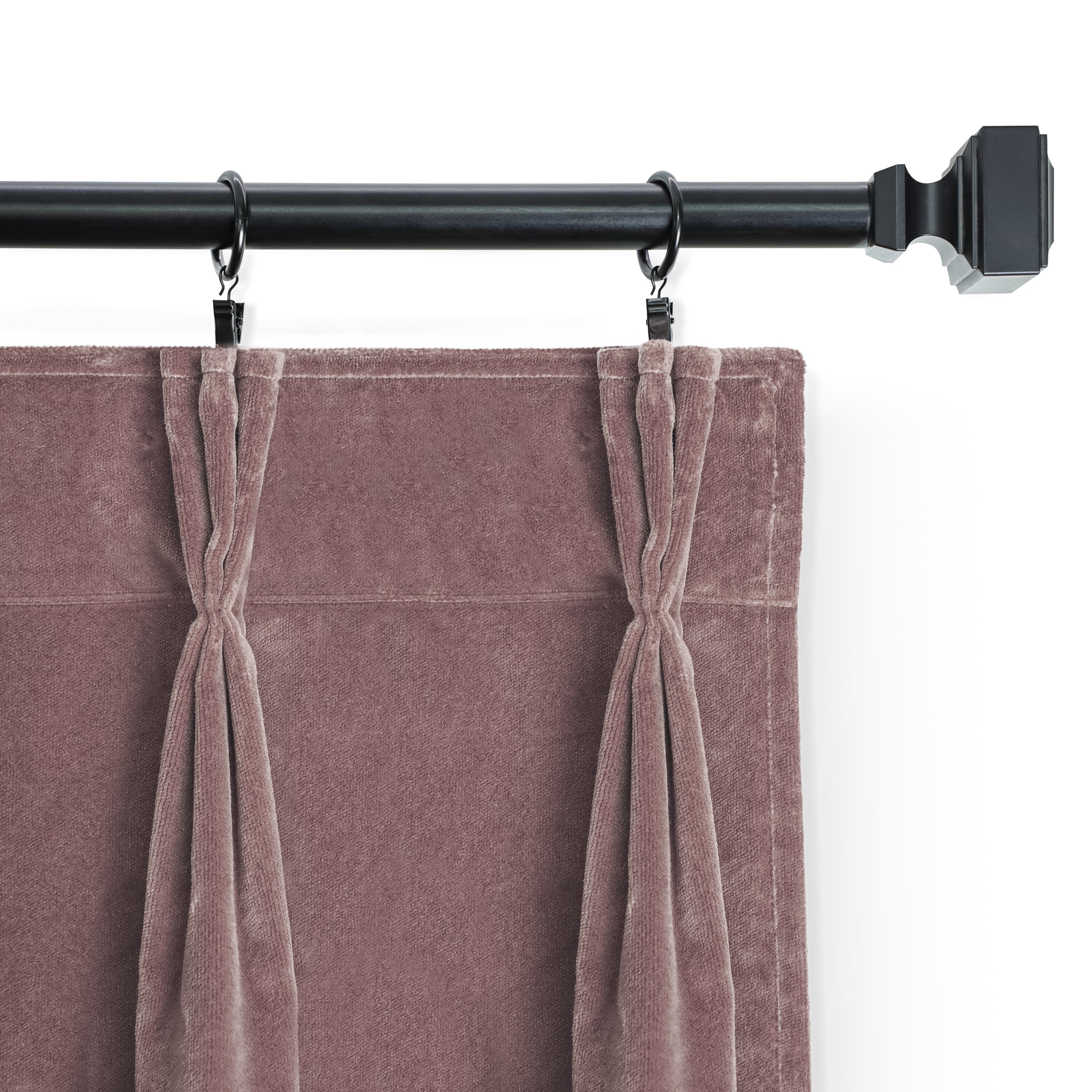 Close-up view of dusty rose cotton velvet curtains hung with black clip rings on a matching matte black rod, highlighting the elegant pinch pleats and soft fabric texture.
