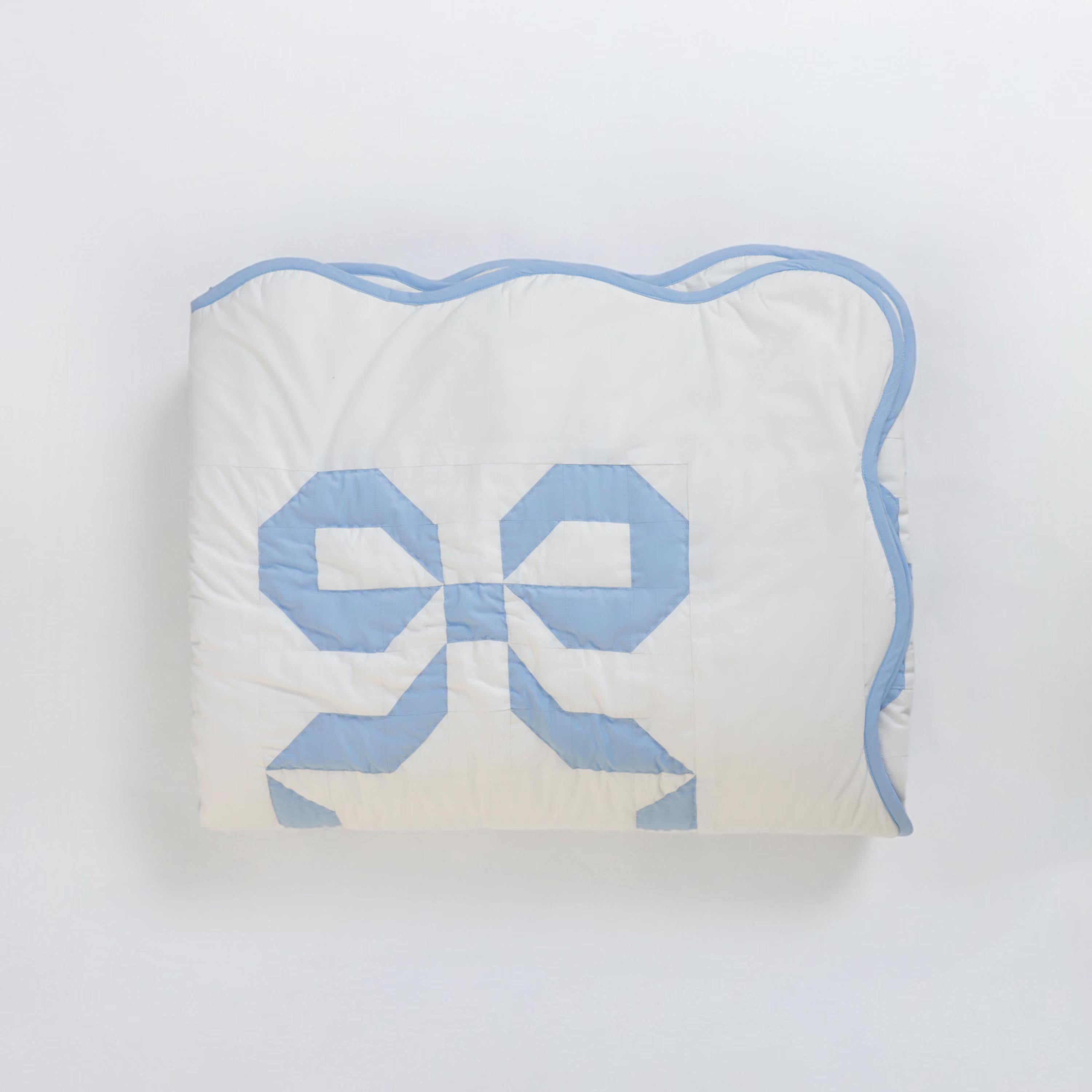 Handmade blue bow patchwork quilt by Amore Beauté, featuring a delicate scalloped edge and soft blue bow design on white cotton. This coquette aesthetic bedding is perfect for girly bedroom decor, preppy dorm rooms, and feminine cottagecore spaces. Our high-quality cotton quilts are ideal for teen girls and nursery decor, offering a vintage-inspired, soft girl interior style. Available in custom sizes including Twin, Queen, and King for a personalized, cozy, and stylish atmosphere.