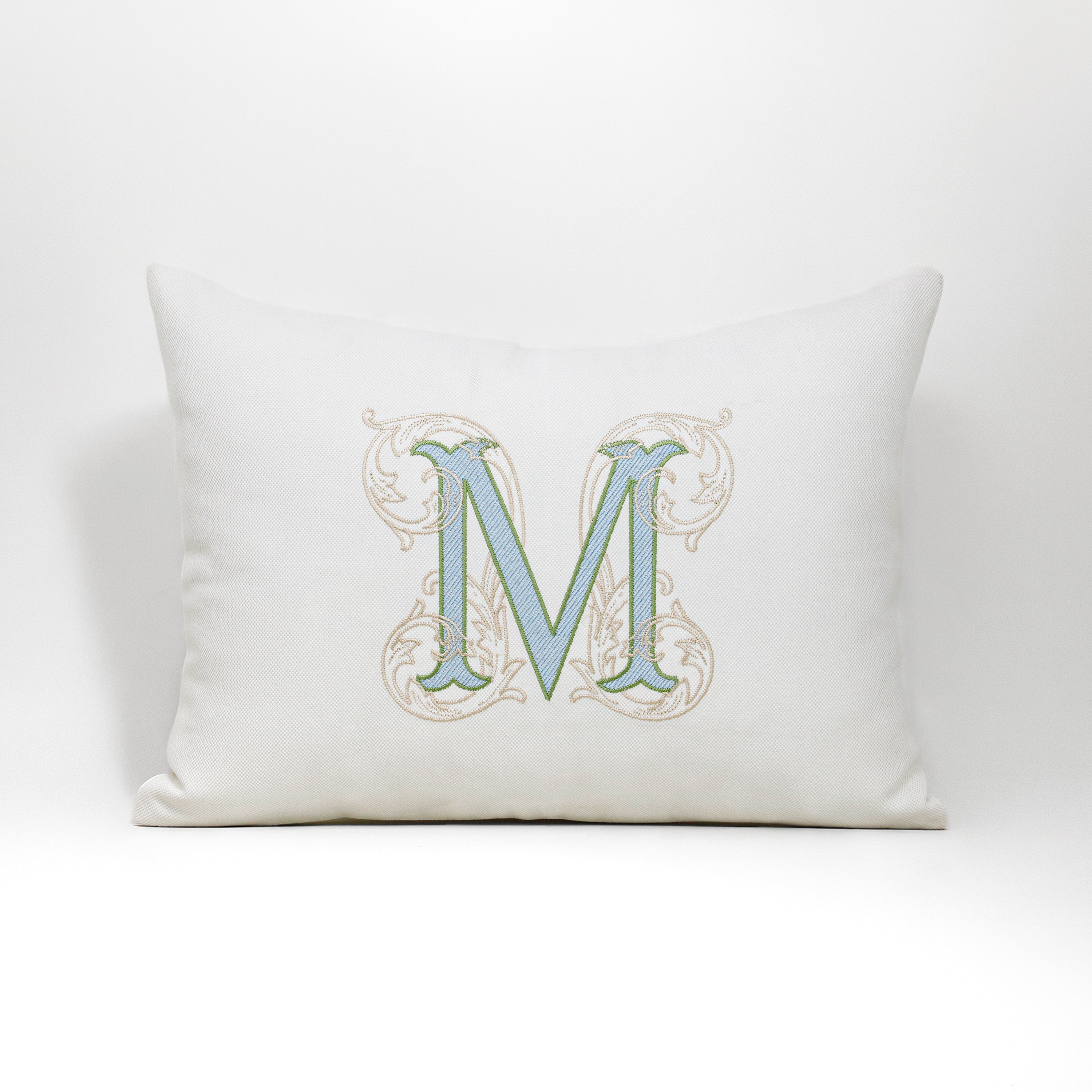 A full top-down view of the personalized ivory cotton canvas pillow cover featuring a detailed vintage-style floral monogram 'M'. The embroidered initial, with light blue fill and light green outline, is centered on the structured cushion cover. Perfect for classic and modern nursery decor, sofa styling, or bedroom accents, this bespoke heirloom piece from Amore Beauté offers exceptional durability and a refined, neutral luxury aesthetic for homeowners and gift buyers.
