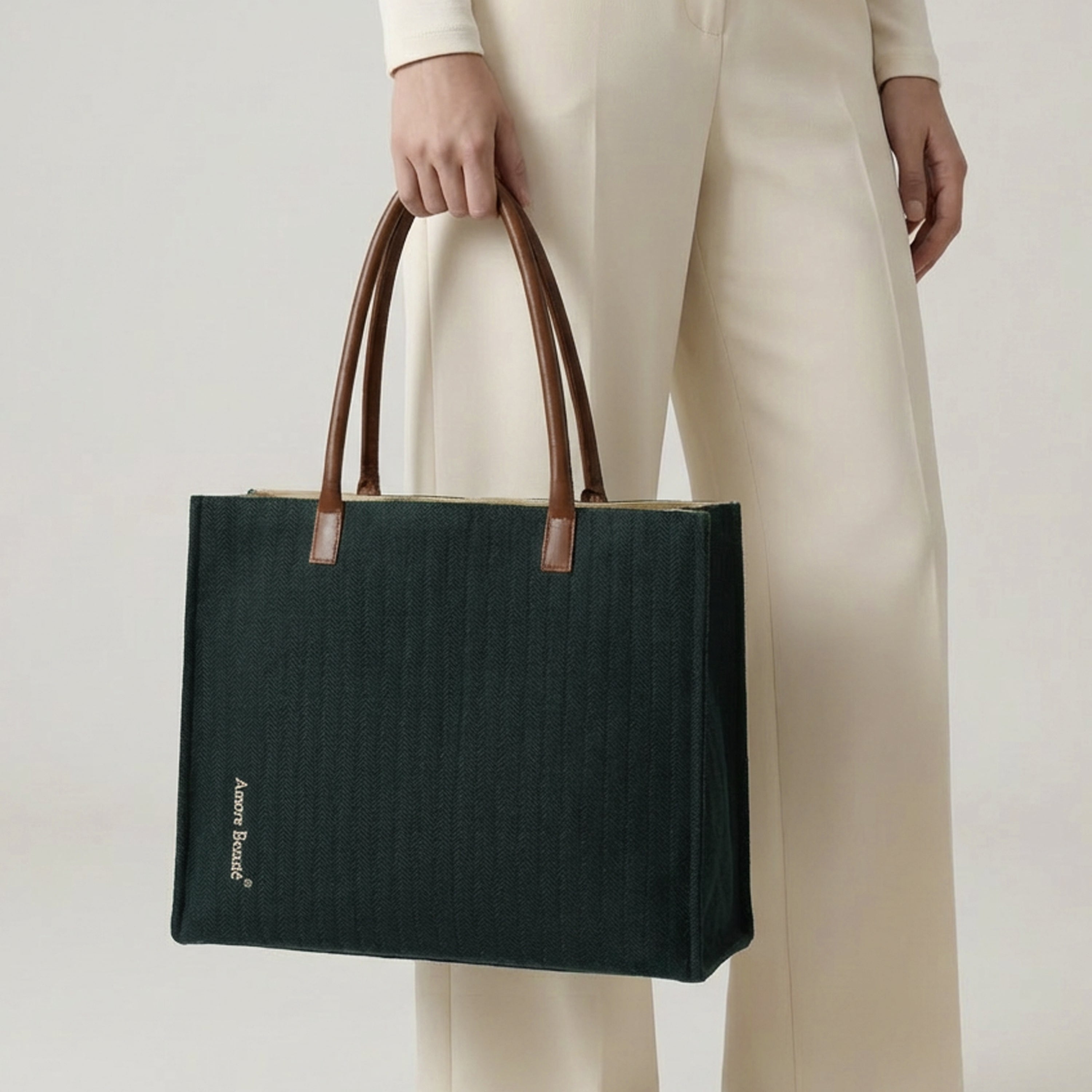 A woman in professional cream-colored attire carrying the large forest green chevron tote bag, demonstrating its scale and elegant drape as a shoulder bag. This lifestyle shot highlights the tote as a perfect professional work bag or travel companion for beach vacations and evening outings. The structured design and textured fabric provide a sophisticated look for modern wardrobes, making it a high-demand item for fashion lovers and travelers. 
