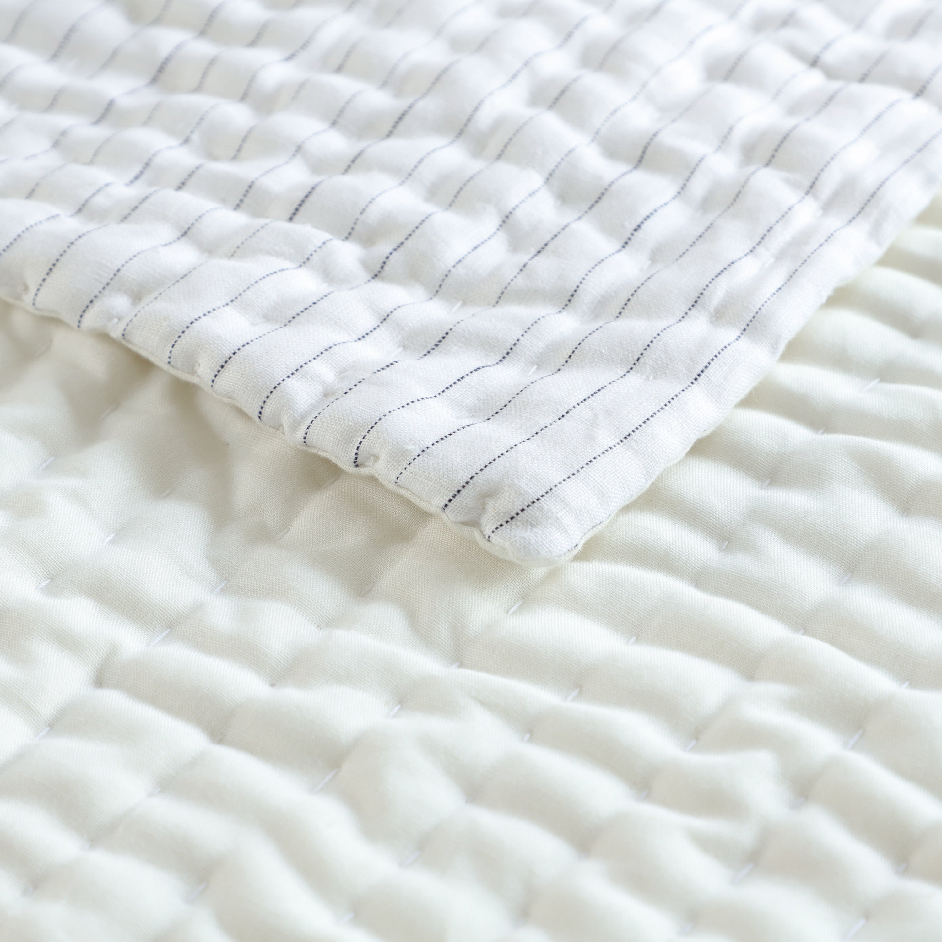 Linen quilt has stitches in similar ivory color. The quilt reverses to ivory cotton and has breathable cotton batting.