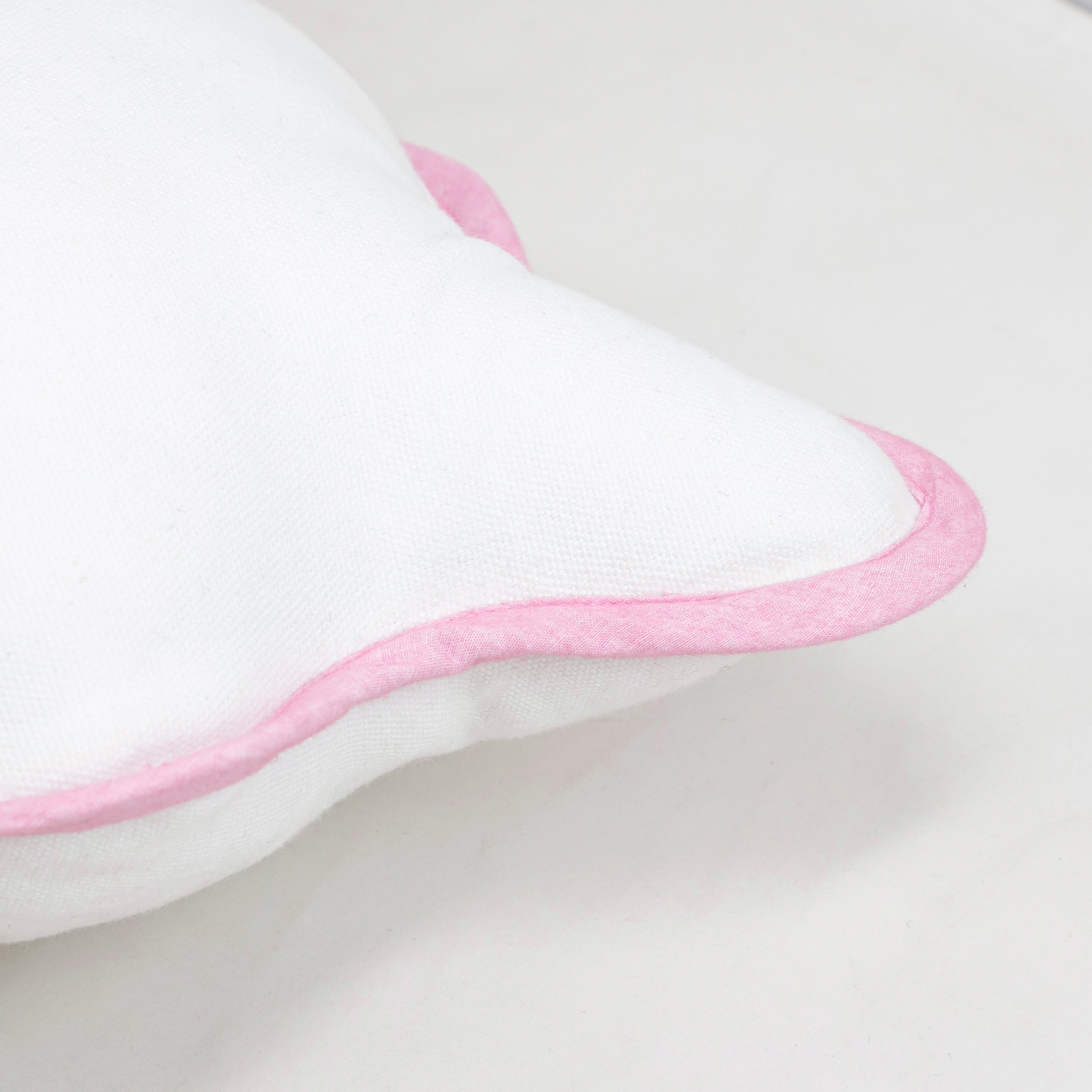 Detailed view of the wavy, scalloped border with pink trim on a white cotton cushion cover. The soft, rounded edges embody a coquette and romantic home aesthetic, making it an ideal choice for nursery bedding or a feminine living room setup. This high-quality cotton fabric is designed for lasting comfort and shape retention, providing a subtle luxury feel to sofas and accent chairs. A popular choice for gift buyers looking for unique, artistic home textiles.