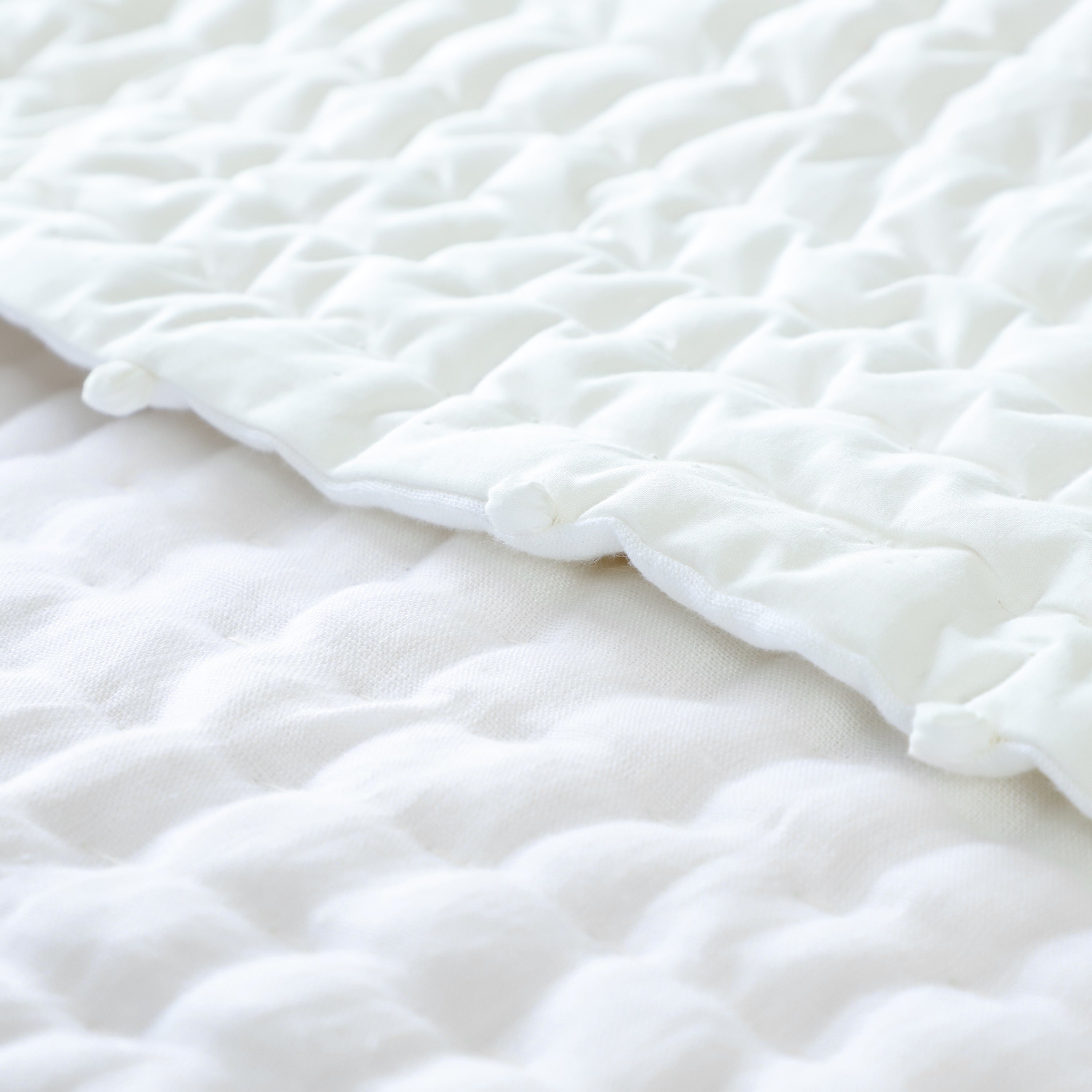 Ivory linen quilt with pompoms on all 4 sides. This all season quilt add textural and tonal look to a bedroom decor.