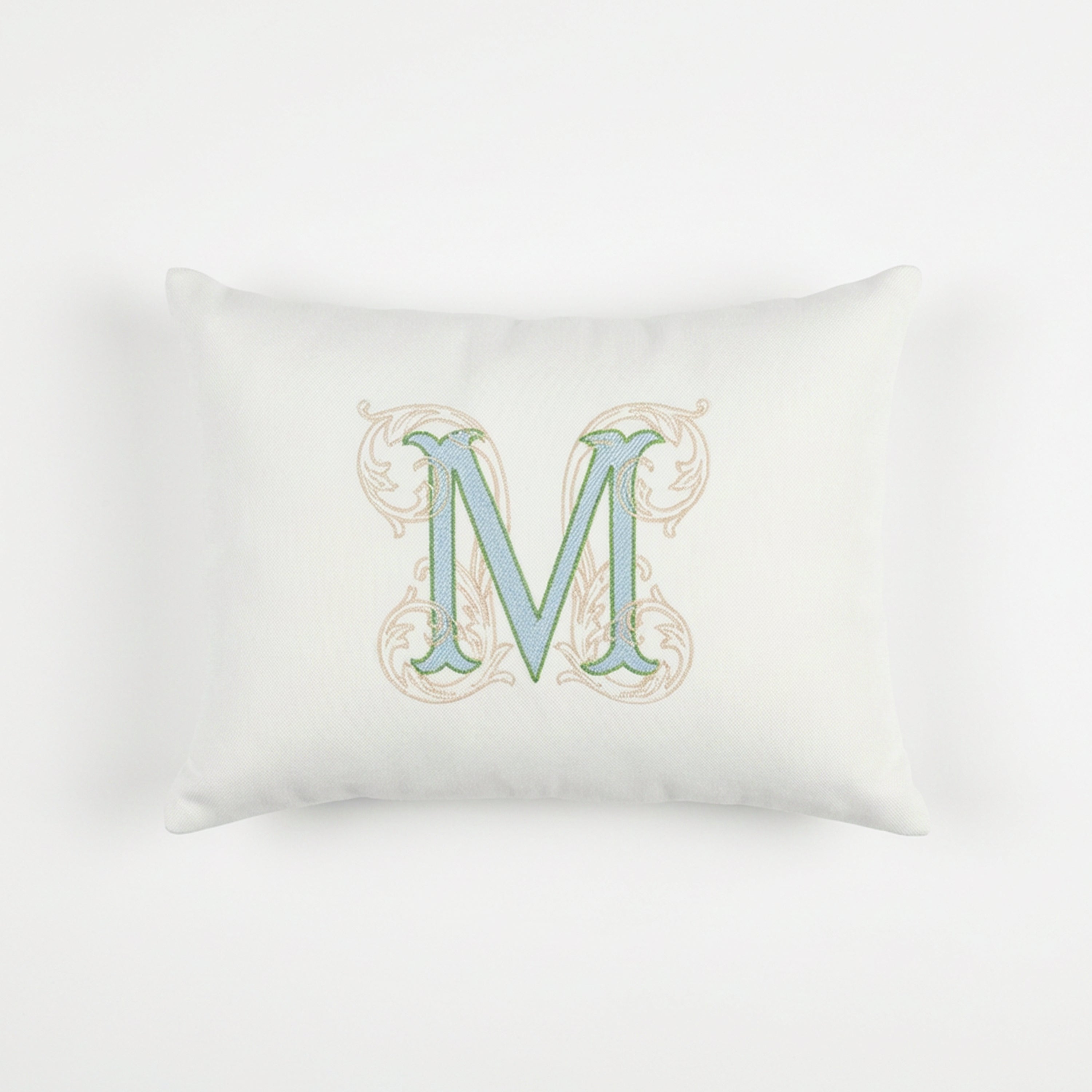 A direct front view of the complete personalized monogram pillow cover, showcasing the vibrant light blue and light green colors of the dense embroidered 'M' motif on the crisp ivory base. The timeless floral initial design offers character and warmth to any space, perfectly complementing traditional and transitional interiors. This customized cotton cushion from Amore Beauté is a thoughtful, durable gift for special occasions and housewarmings.