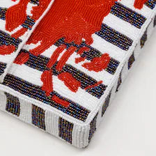 Corner and edge detail highlighting the continuous striped pattern of the Handmade Beaded Crab Clutch.