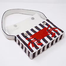 Handmade Beaded Crab Clutch with its front flap completely flipped open, revealing two silver magnetic snap fasteners on the white fabric underside. The lower section showcases the red beaded crab pattern across the striped exterior.