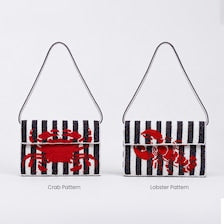 On the left is the black and white striped Handmade Beaded Crab Clutch featuring a red crab pattern. On the right is a matching striped clutch featuring a red lobster pattern.