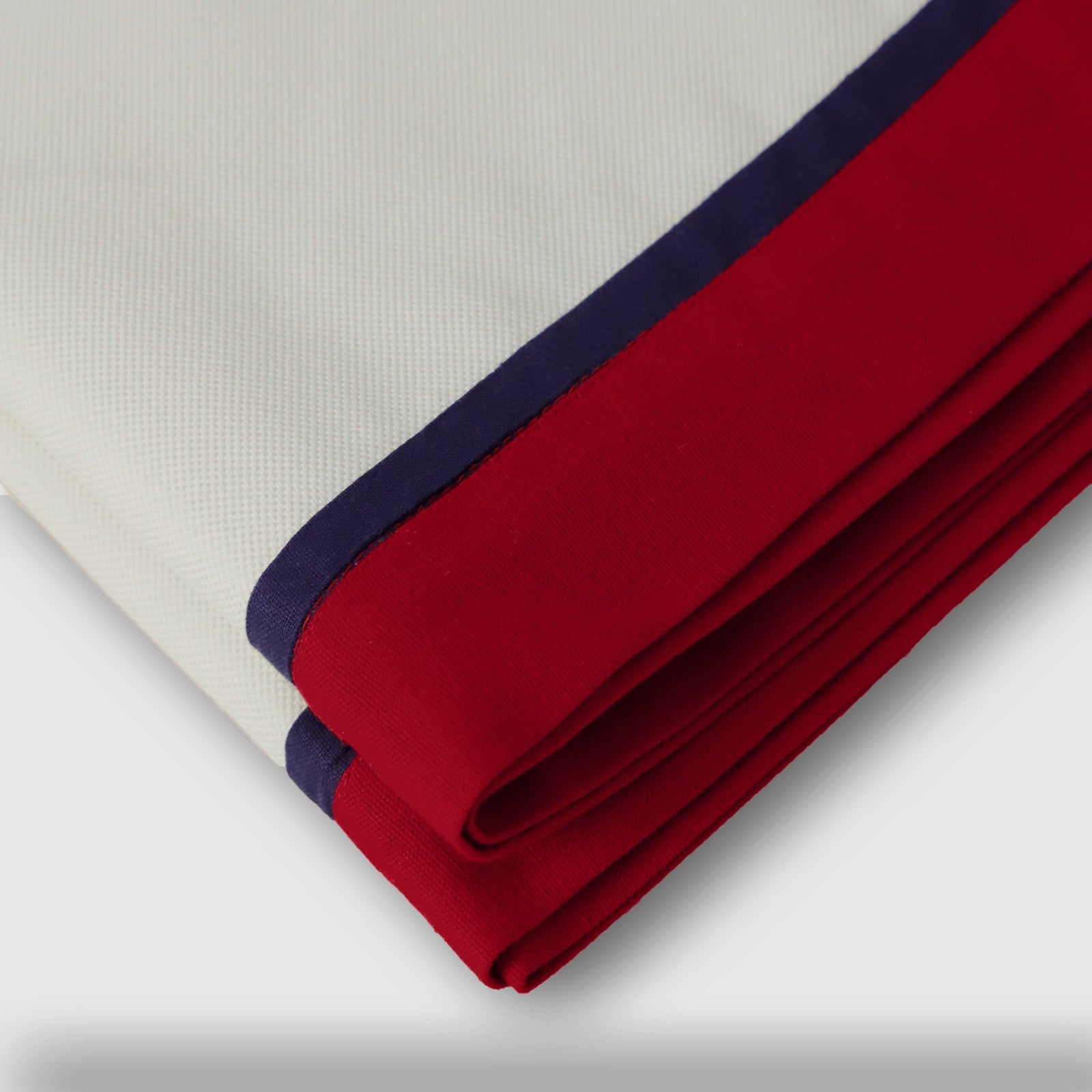 Fabric detail of the Ivory Table Runner With Custom Border showing navy blue and red stitched trim.
