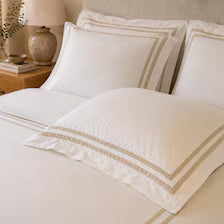 White 400TC duvet cover and four decorative pillows with beige trim. 