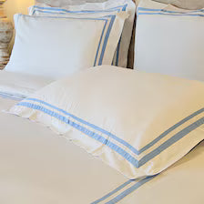 400 Thread count satin cotton duvet cover set with light blue trim with four pillows featuring light blue striped borders.