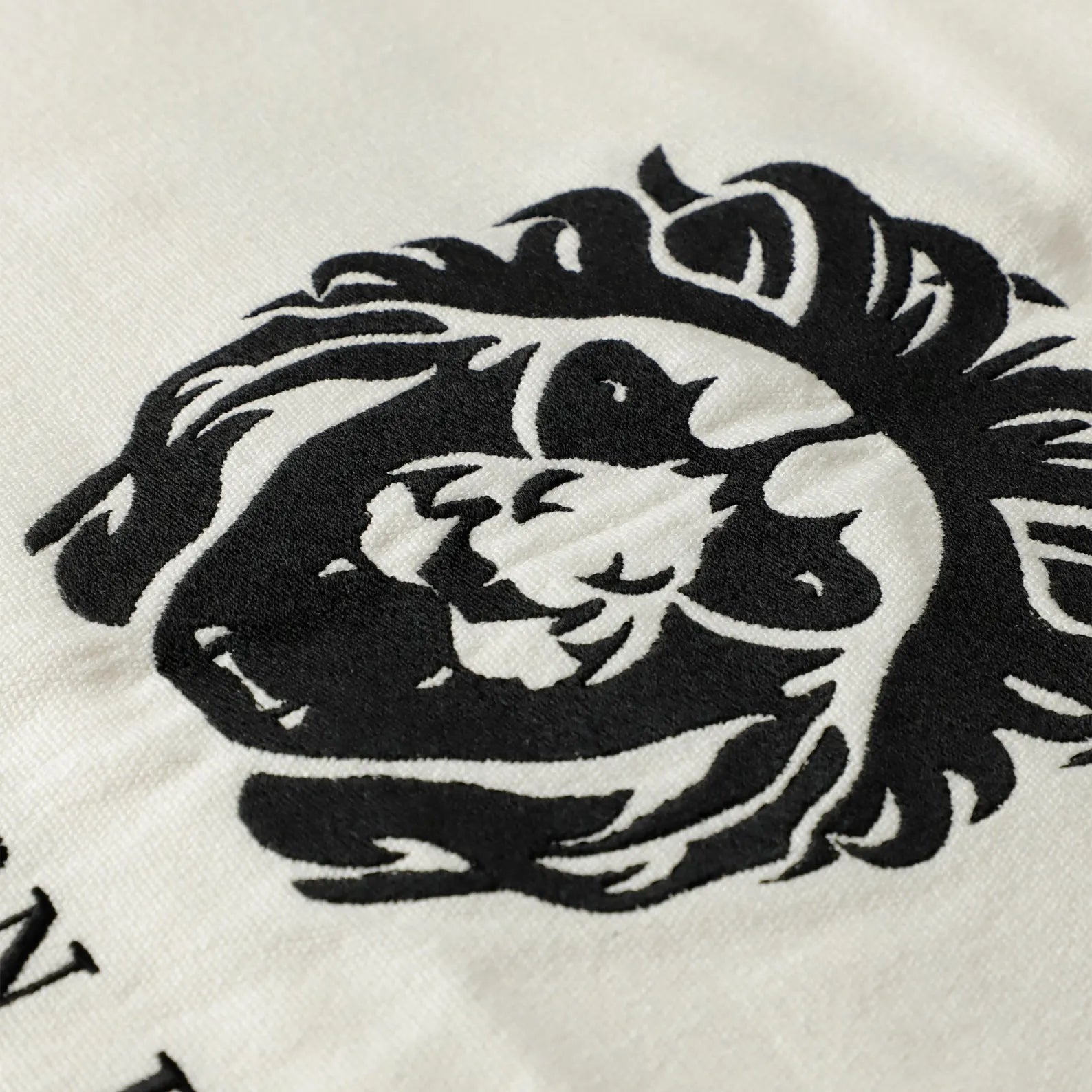 Detailed view of custom black embroidery on an ivory shower curtain, featuring a sophisticated lion logo and "The Southern Building Washington, D.C." text. This personalized monogramming service by Amore Beauté allows for custom initials, brand names, or logos on luxury bathroom curtains. The high-contrast black embroidery on a crisp ivory base is perfect for creating a memorable, bespoke finishing touch in salon, spa, or high-end residential interiors.