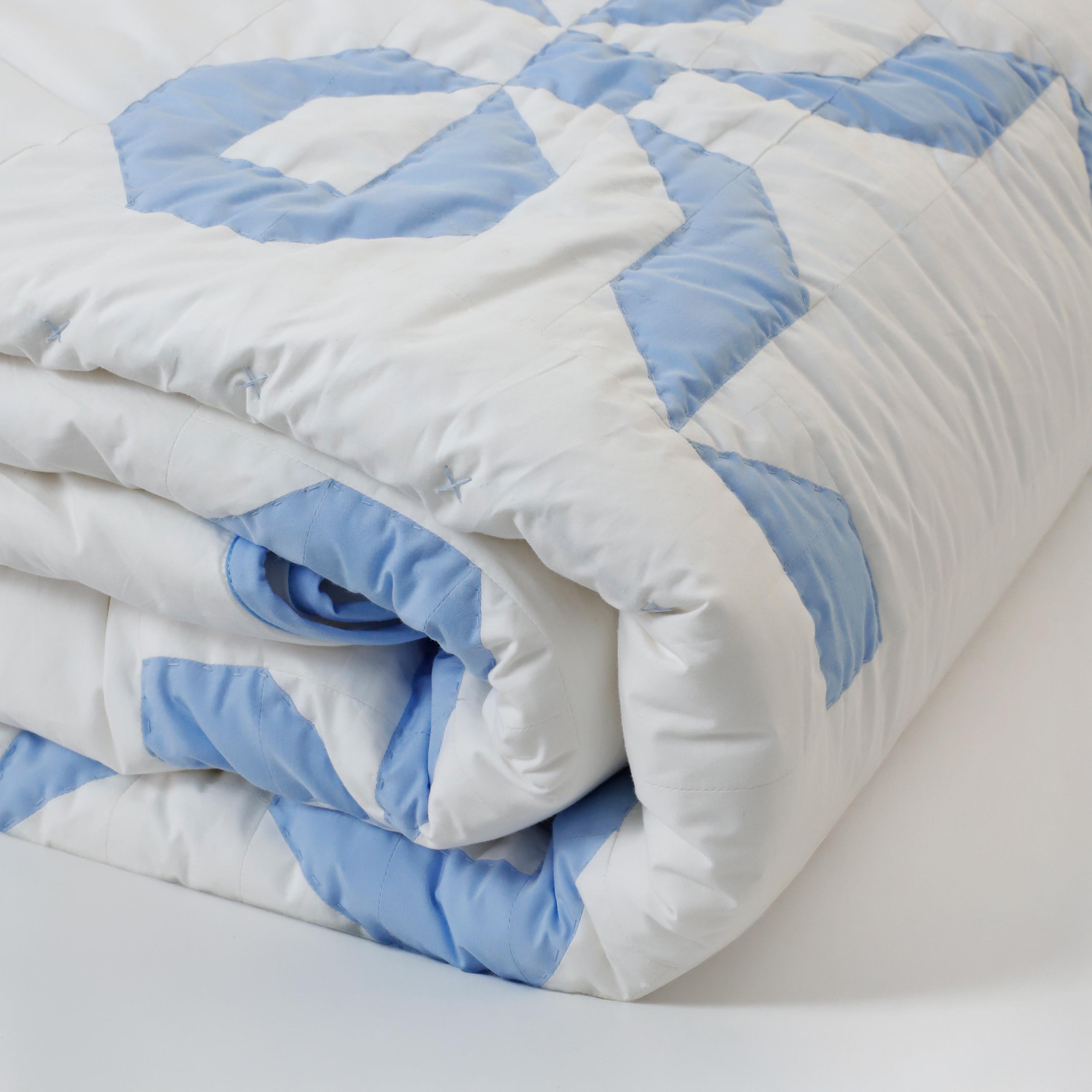 A side view of the folded blue bow patchwork quilt, highlighting the soft, breathable cotton layers and scalloped border detailing. Perfect for spring-summer decor and cozy winter layering, this blue and white girly bedding fits seamlessly into cottagecore and soft girl bedroom themes. Designed for durability and comfort, our custom-size quilts are a top choice for US and UK markets in dorm decor and nursery bedding. Experience handcrafted luxury with this timeless, playful bow design.