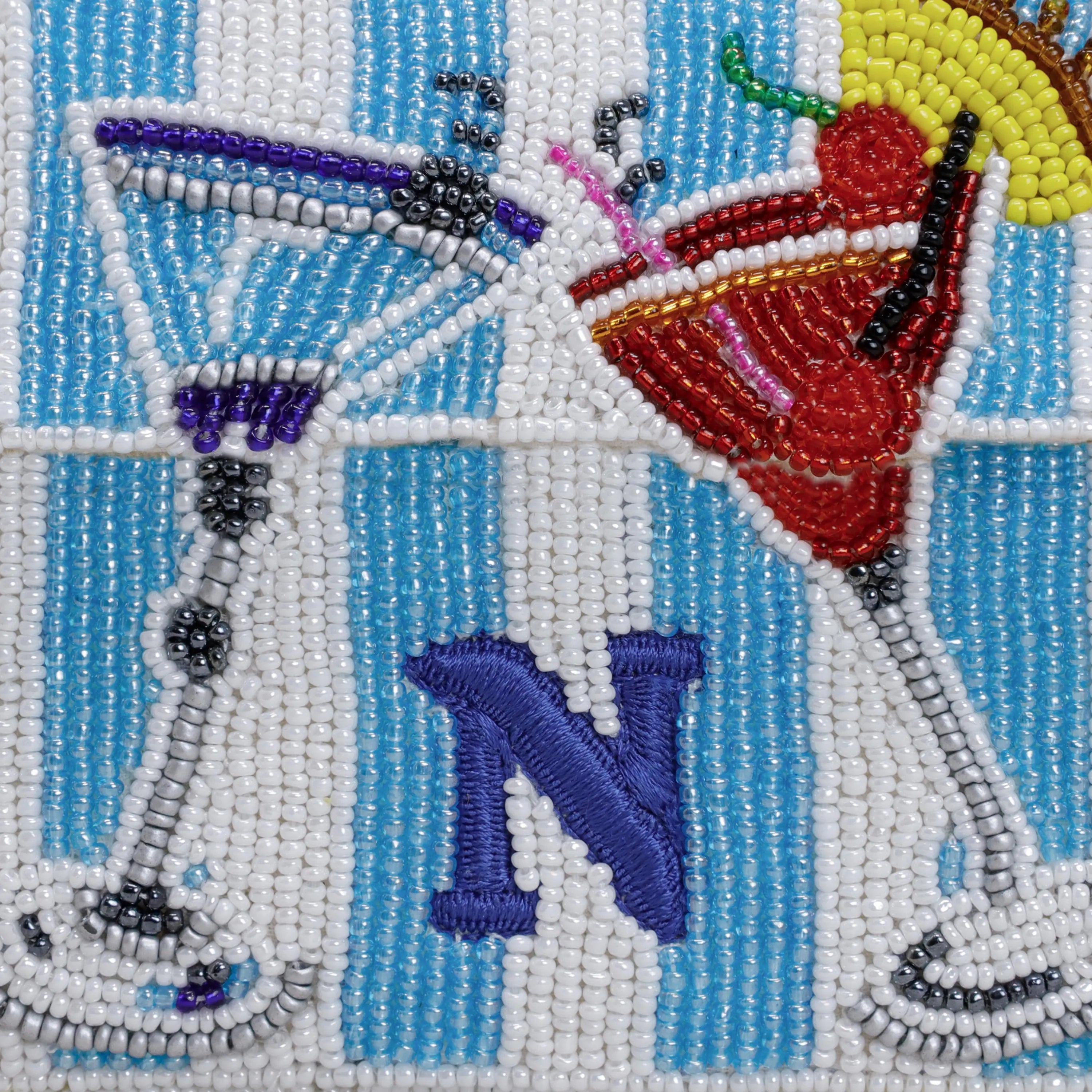 A detailed close-up of the hand-beaded embroidery on the Amore Beauté striped purse, showcasing the intricate martini glass, colorful fruits, and a custom blue monogram letter 'N'. This macro shot highlights the durable, artisan-crafted quality and vibrant bead colors. It demonstrates our customization option - we can personalize the design with your preferred monogram, size, or colorway. A luxurious, one-of-a-kind accessory for cocktail lovers and collectors of unique handmade pieces.