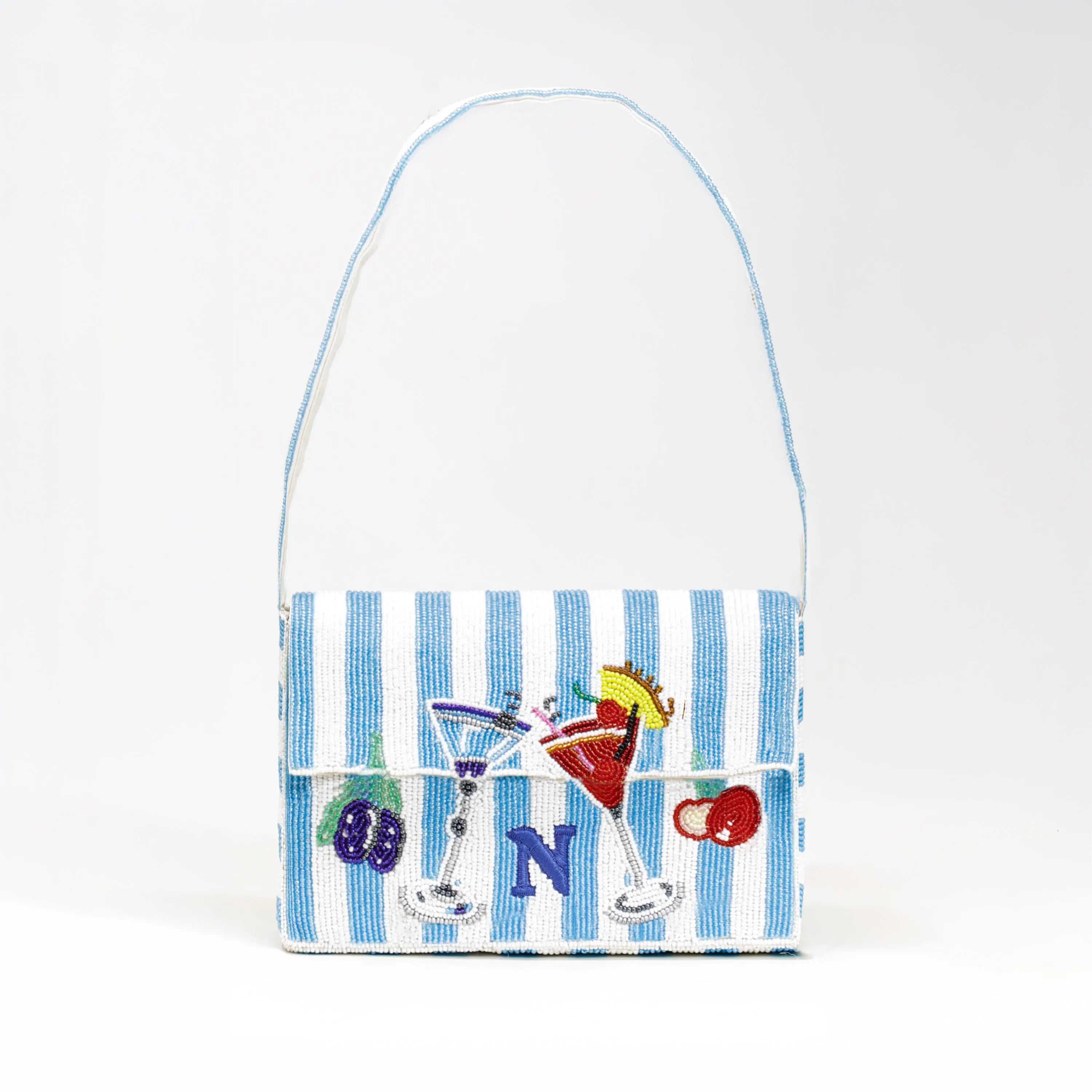 A full view of the hand-beaded cocktail themed mini shoulder bag against a neutral background. The bag features a fresh blue and white striped base, detailed martini and fruit embroidery, and a prominent personalized blue 'N' monogram. Amore Beauté’s luxury designer purse has a beaded handle and offers standout style for summer parties, vacations, and brunches. A durable, artisan-crafted statement handbag that adds a playful touch to any outfit. A thoughtful, unique gift for travelers and fashion lovers.