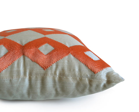 Handmade ivory throw pillow with orange ikat embroidery